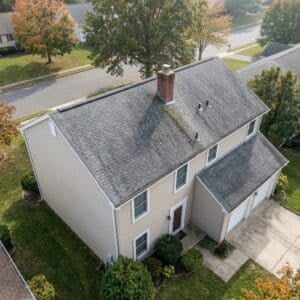 Aerial view of a two-story New Jersey home with an aging, moss-streaked asphalt shingle roof